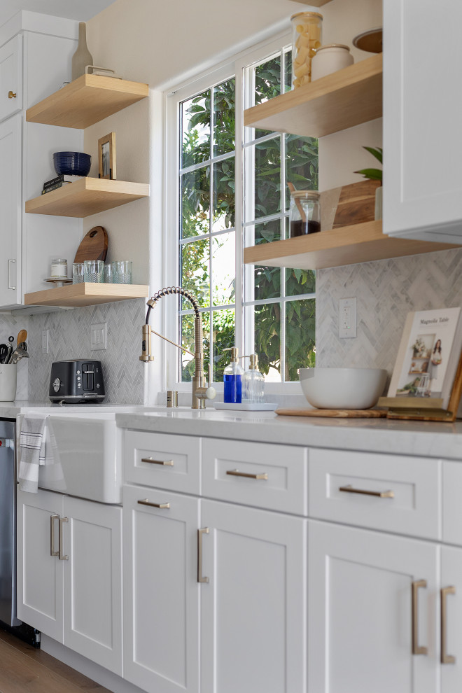 Bild på ett mellanstort funkis vit vitt kök, med en rustik diskho, luckor med infälld panel, vita skåp, marmorbänkskiva, vitt stänkskydd, rostfria vitvaror, ljust trägolv, en köksö och brunt golv