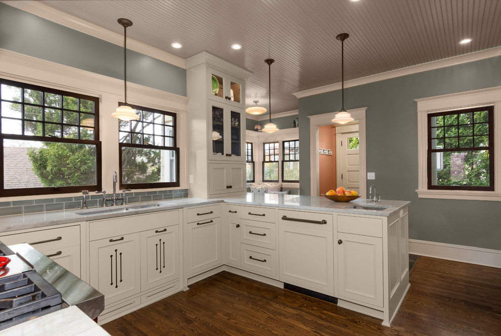 Mid-sized transitional u-shaped medium tone wood floor and brown floor enclosed kitchen photo in Seattle with an undermount sink, beaded inset cabinets, gray cabinets, quartzite countertops, gray backsplash, ceramic backsplash, paneled appliances and a peninsula