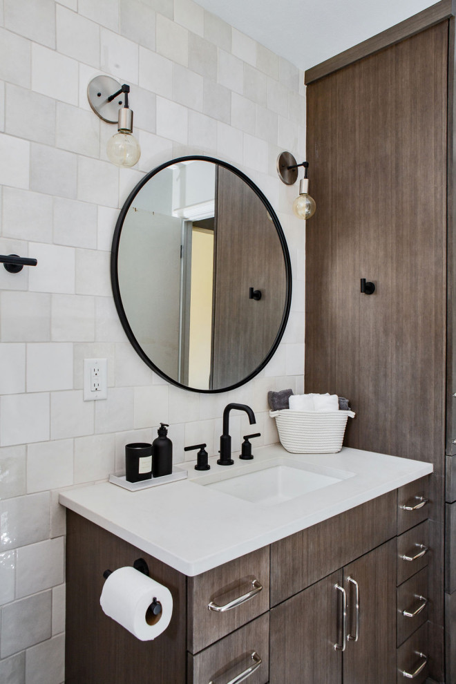 Design ideas for a medium sized country family bathroom in Denver with flat-panel cabinets, medium wood cabinets, an alcove bath, an alcove shower, a one-piece toilet, white tiles, ceramic tiles, white walls, mosaic tile flooring, a submerged sink, engineered stone worktops, black floors, a shower curtain, white worktops, a wall niche, a single sink and a built in vanity unit.