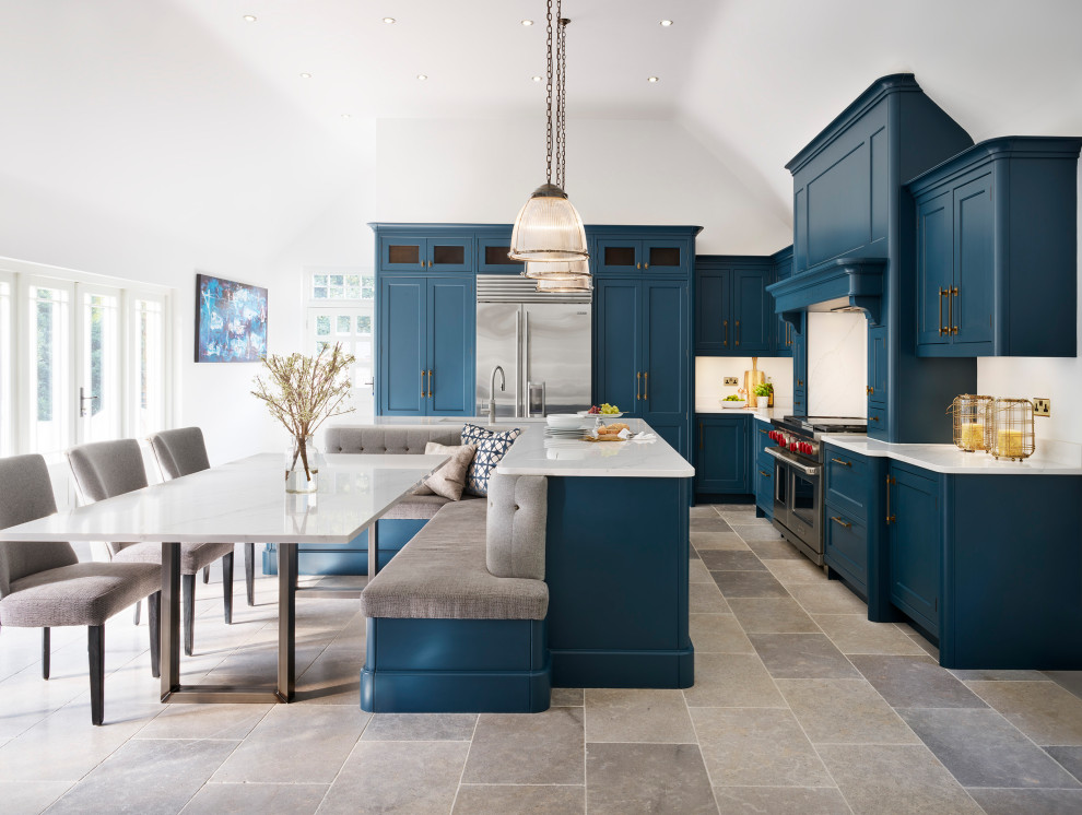 Photo of a transitional u-shaped eat-in kitchen in Essex with shaker cabinets, blue cabinets, quartzite benchtops, white splashback, stainless steel appliances, with island, white benchtop, an undermount sink, multi-coloured floor and vaulted.