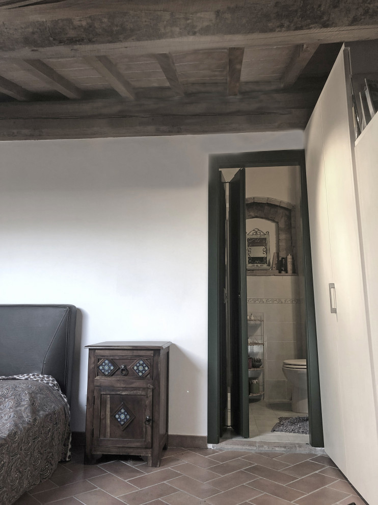 フィレンツェにある小さなおしゃれな主寝室 (ベージュの壁、テラコッタタイルの床、茶色い床、表し梁) のレイアウト