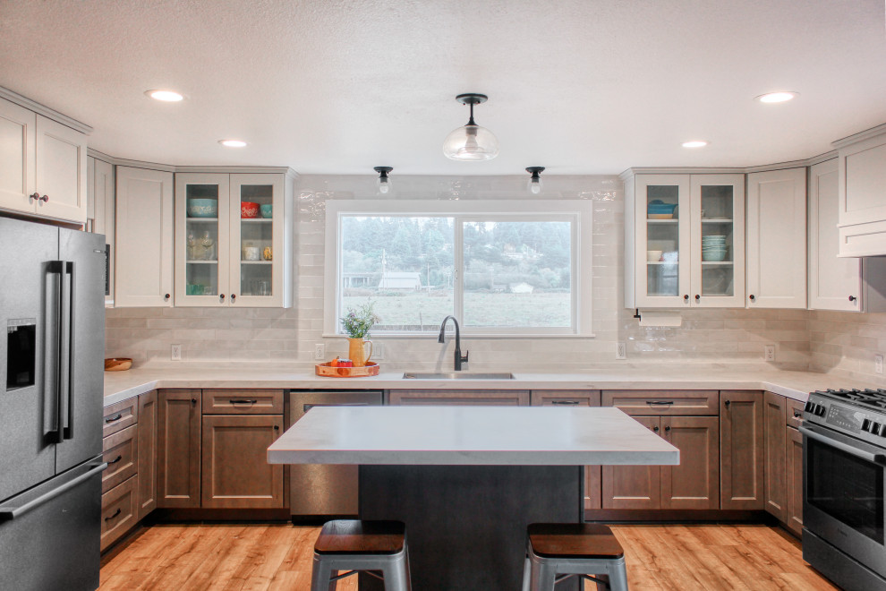 Inspiration for a mid-sized transitional u-shaped light wood floor and brown floor eat-in kitchen remodel with an undermount sink, recessed-panel cabinets, medium tone wood cabinets, solid surface countertops, white backsplash, ceramic backsplash, stainless steel appliances, an island and white countertops