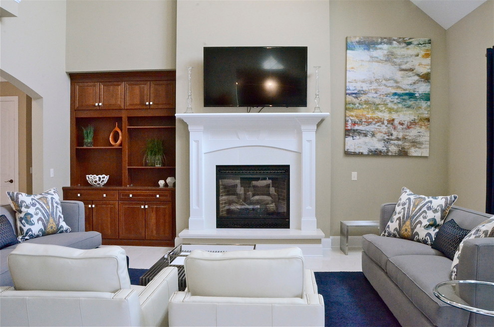 Photo of a large transitional open concept family room in Charlotte with beige walls, a standard fireplace, a tile fireplace surround, a wall-mounted tv, white floor and porcelain floors.