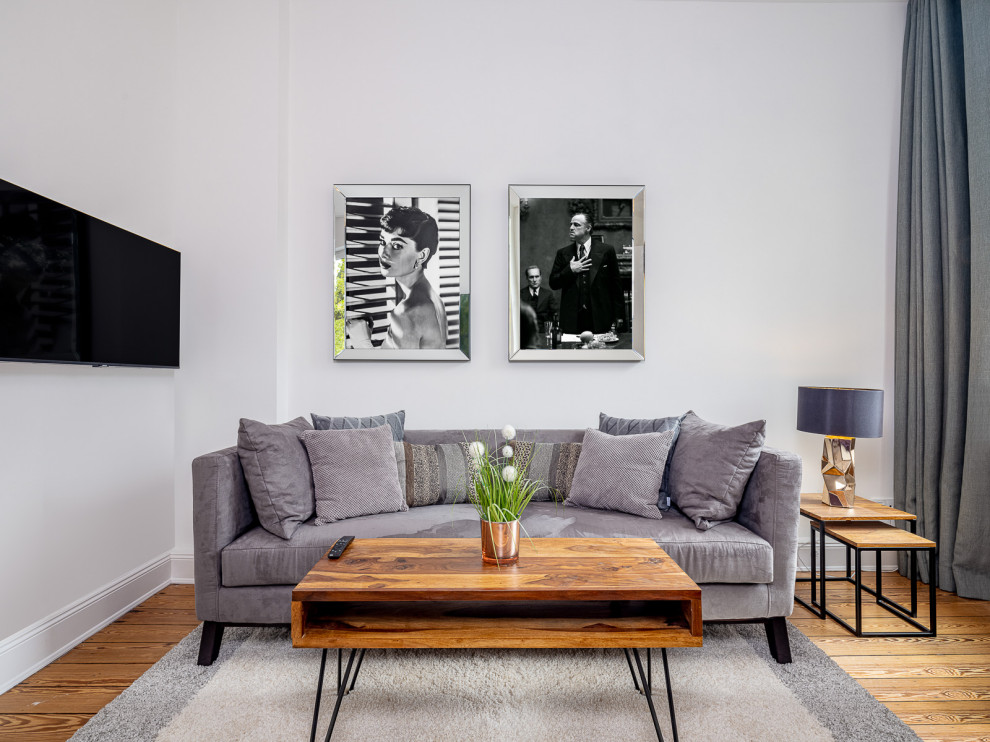 Immagine di un piccolo soggiorno mediterraneo chiuso con pareti bianche, TV a parete, pavimento marrone, carta da parati e pavimento in legno verniciato