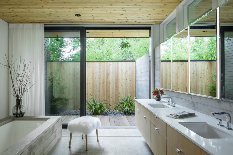 This is an example of a midcentury bathroom in Portland with light wood cabinets, an undermount tub, an undermount sink, grey floor, white benchtops and flat-panel cabinets.