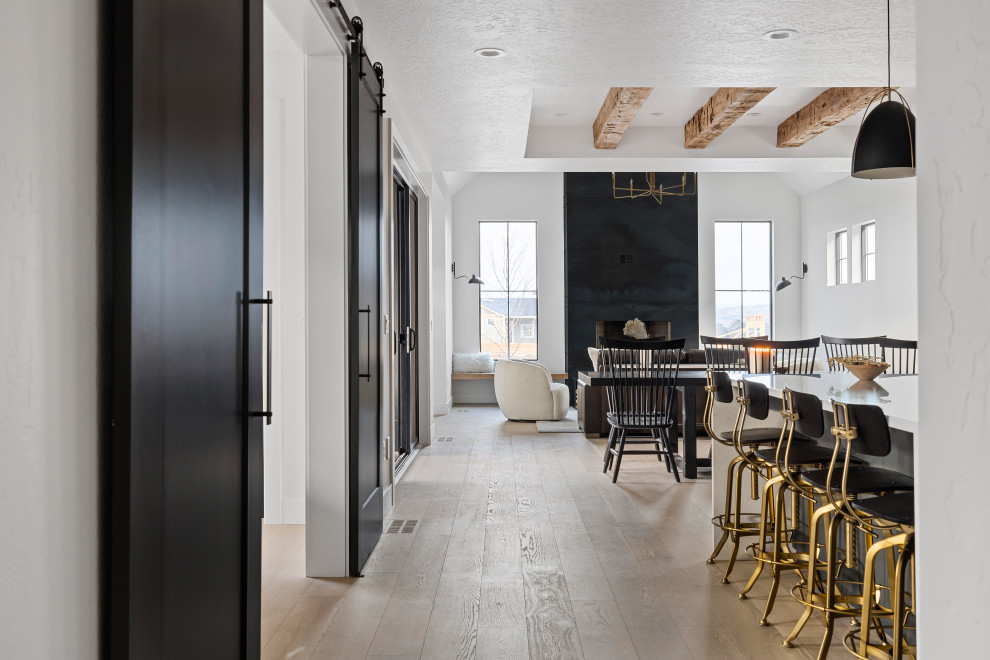 Exemple d'une salle à manger ouverte sur le salon scandinave de taille moyenne avec un mur blanc, parquet clair, un poêle à bois, un manteau de cheminée en métal, un sol beige et poutres apparentes.