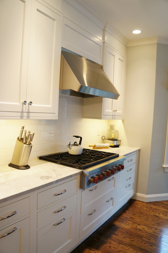 Open concept kitchen - large transitional galley dark wood floor open concept kitchen idea in Boston with beaded inset cabinets, white cabinets, quartzite countertops, white backsplash, subway tile backsplash, stainless steel appliances and an island