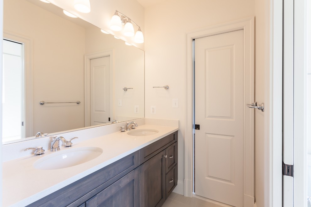 Example of a transitional kids' beige floor bathroom design in DC Metro with medium tone wood cabinets, white walls, an undermount sink, granite countertops, a hinged shower door and beige countertops