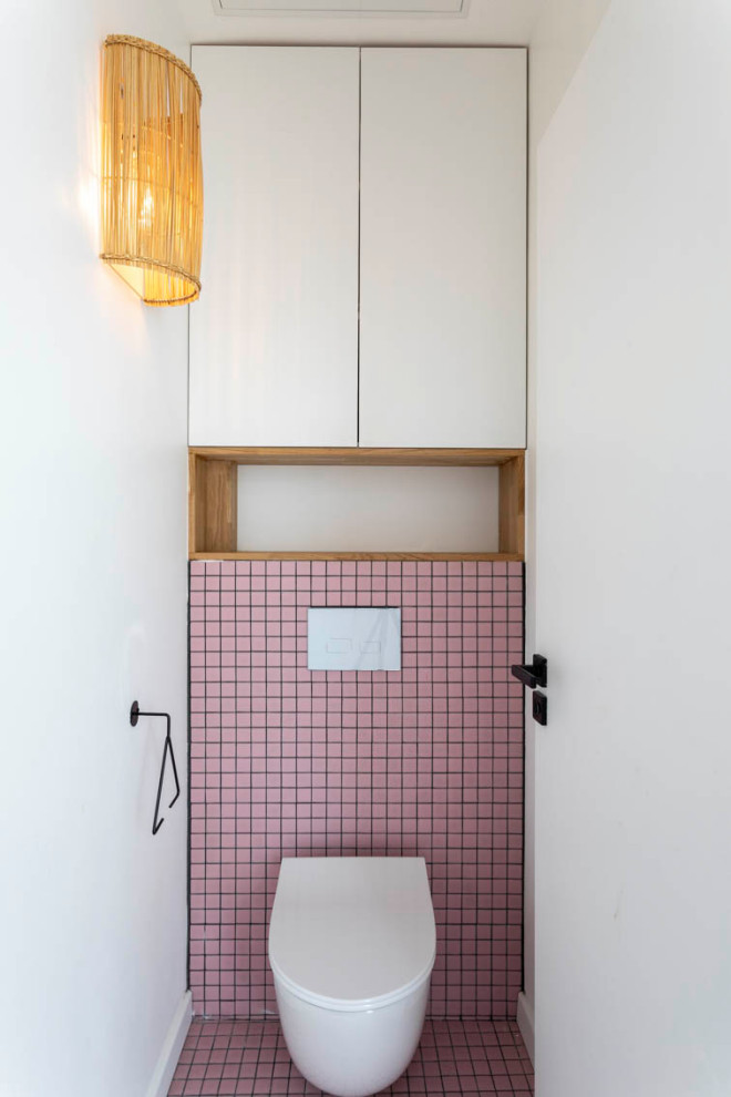 Small cloakroom in Paris with beaded cabinets, white cabinets, a wall mounted toilet, pink tiles, ceramic tiles, white walls, ceramic flooring, pink floors and a built in vanity unit.