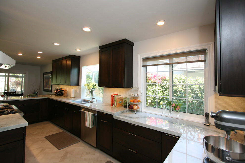 Mid-sized transitional l-shaped porcelain tile kitchen photo in Orange County with a double-bowl sink, recessed-panel cabinets, dark wood cabinets, quartzite countertops, white backsplash, glass tile backsplash, stainless steel appliances and no island