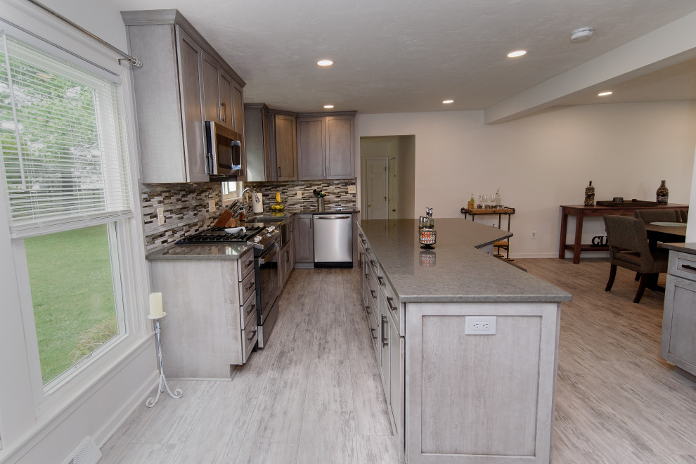 Large transitional u-shaped gray floor eat-in kitchen photo in Baltimore with a farmhouse sink, shaker cabinets, gray cabinets, quartz countertops, multicolored backsplash, glass tile backsplash, stainless steel appliances, an island and gray countertops
