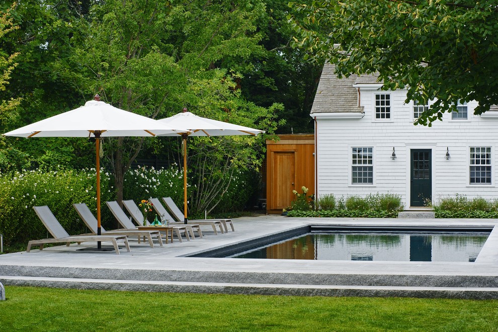 Design ideas for a mid-sized contemporary backyard rectangular pool in Boston with a pool house and natural stone pavers.