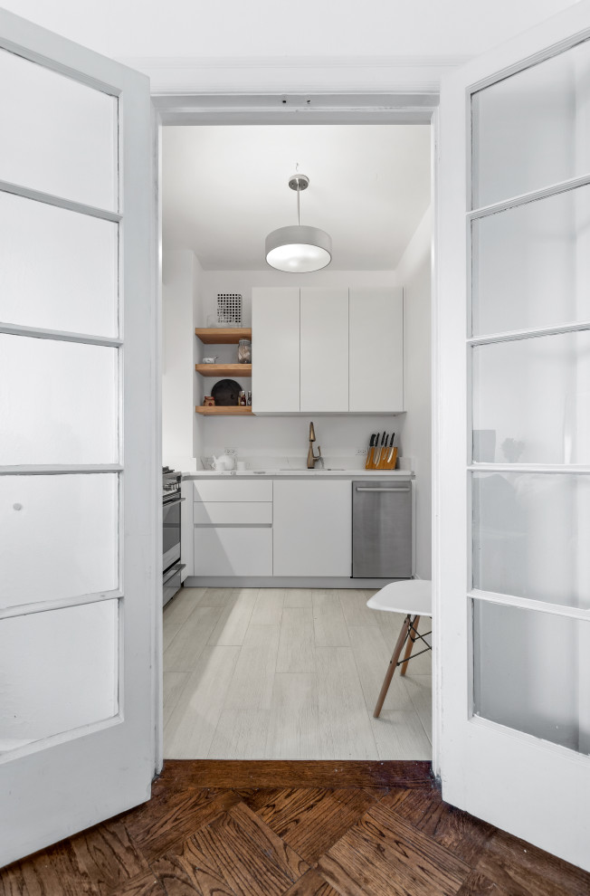 Mid-sized transitional l-shaped light wood floor enclosed kitchen photo in Chicago with an undermount sink, flat-panel cabinets, white cabinets, marble countertops, white backsplash, subway tile backsplash, stainless steel appliances, no island and white countertops