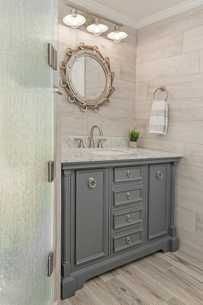 Inspiration for a large beach style master bathroom in Tampa with shaker cabinets, grey cabinets, a drop-in tub, a corner shower, a two-piece toilet, multi-coloured tile, ceramic tile, blue walls, ceramic floors, an undermount sink, granite benchtops, beige floor, a hinged shower door and multi-coloured benchtops.