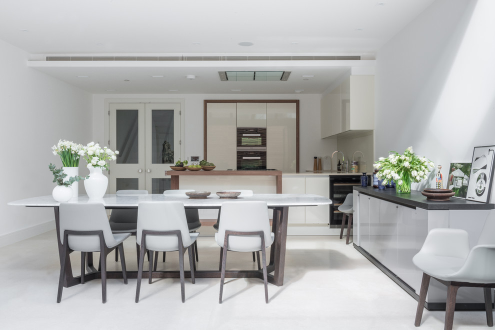 Design ideas for a large contemporary eat-in kitchen in London with a double-bowl sink, beige cabinets, limestone benchtops, beige splashback, glass sheet splashback, panelled appliances and with island.