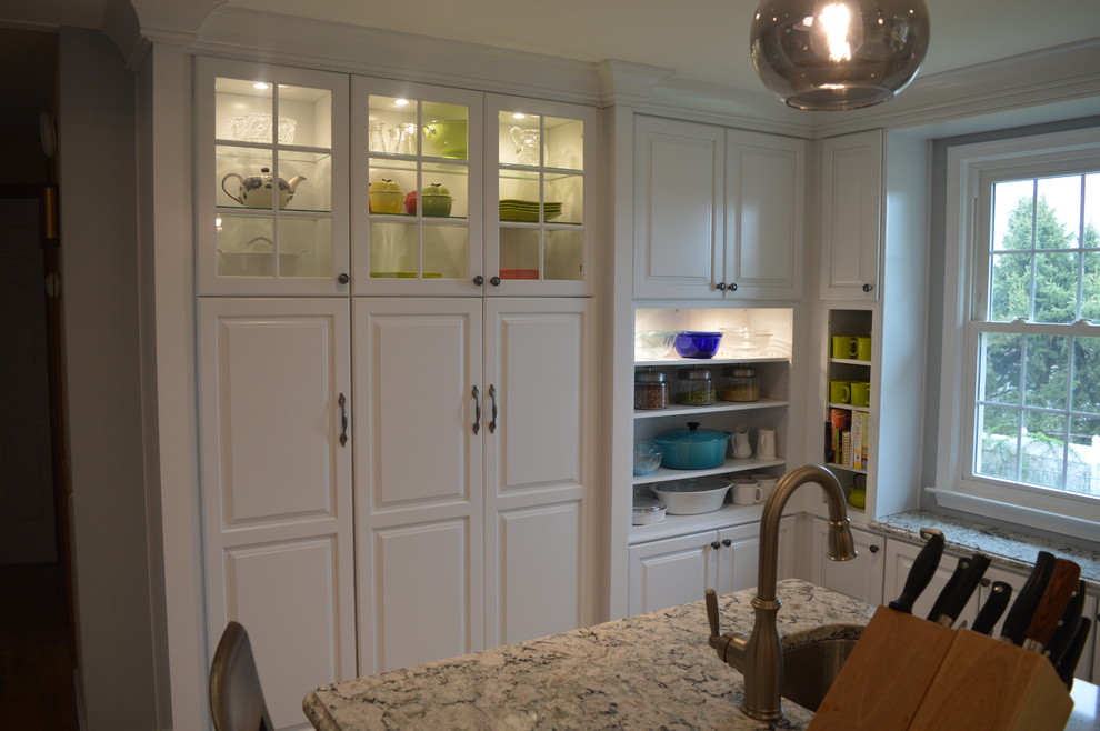 Example of a large transitional u-shaped ceramic tile and gray floor home design design with a farmhouse sink, raised-panel cabinets, white cabinets, quartz countertops, gray backsplash, glass tile backsplash, stainless steel appliances and an island