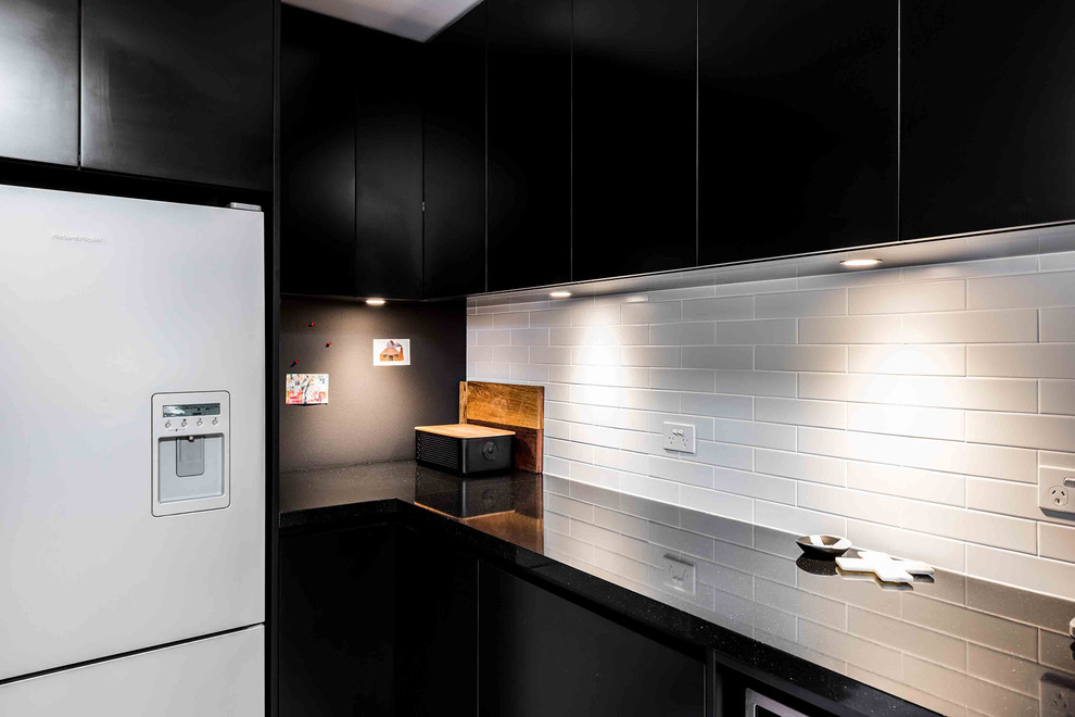 Inspiration for a contemporary eat-in kitchen in Melbourne with an undermount sink, flat-panel cabinets, black cabinets, quartz benchtops, orange splashback, cement tile splashback, stainless steel appliances, medium hardwood floors and no island.