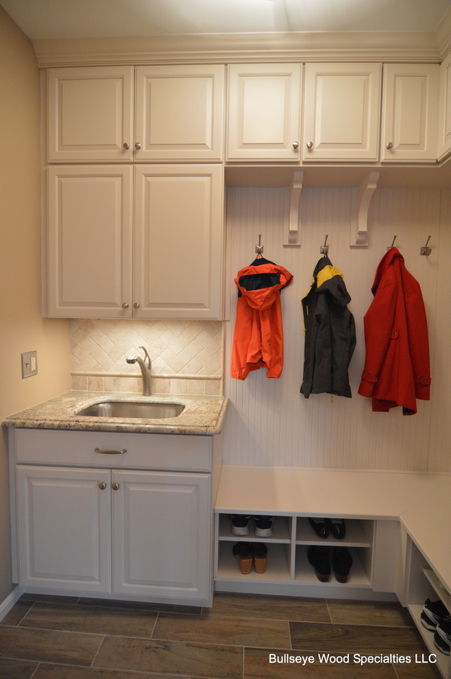 This is an example of a small traditional mudroom in DC Metro with white walls, ceramic floors and brown floor.
