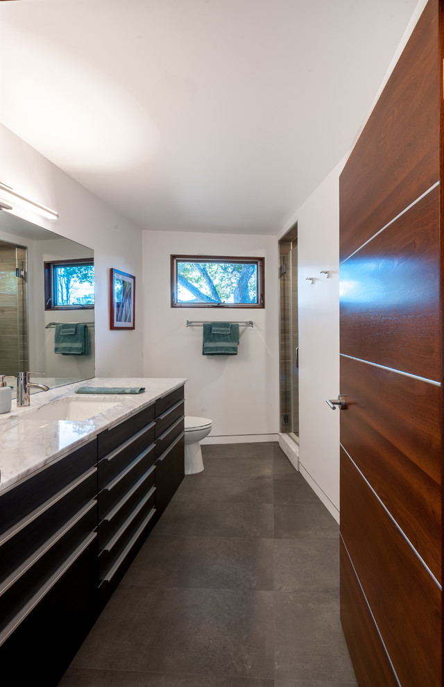 Photo of a mid-sized midcentury master bathroom in San Francisco with flat-panel cabinets, black cabinets, a corner tub, a shower/bathtub combo, a one-piece toilet, white tile, porcelain tile, white walls, cement tiles and solid surface benchtops.