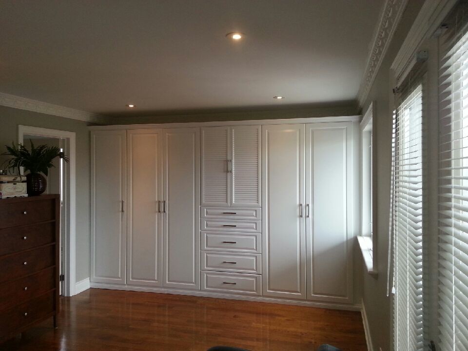 Photo of a large traditional gender-neutral built-in wardrobe in Toronto with raised-panel cabinets, white cabinets and medium hardwood floors.