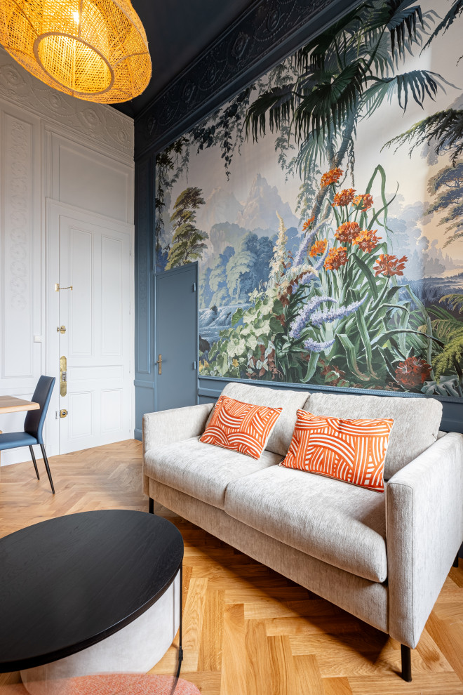 Modelo de sala de estar cerrada clásica renovada pequeña sin chimenea y televisor con paredes azules, suelo de madera clara, suelo marrón y papel pintado