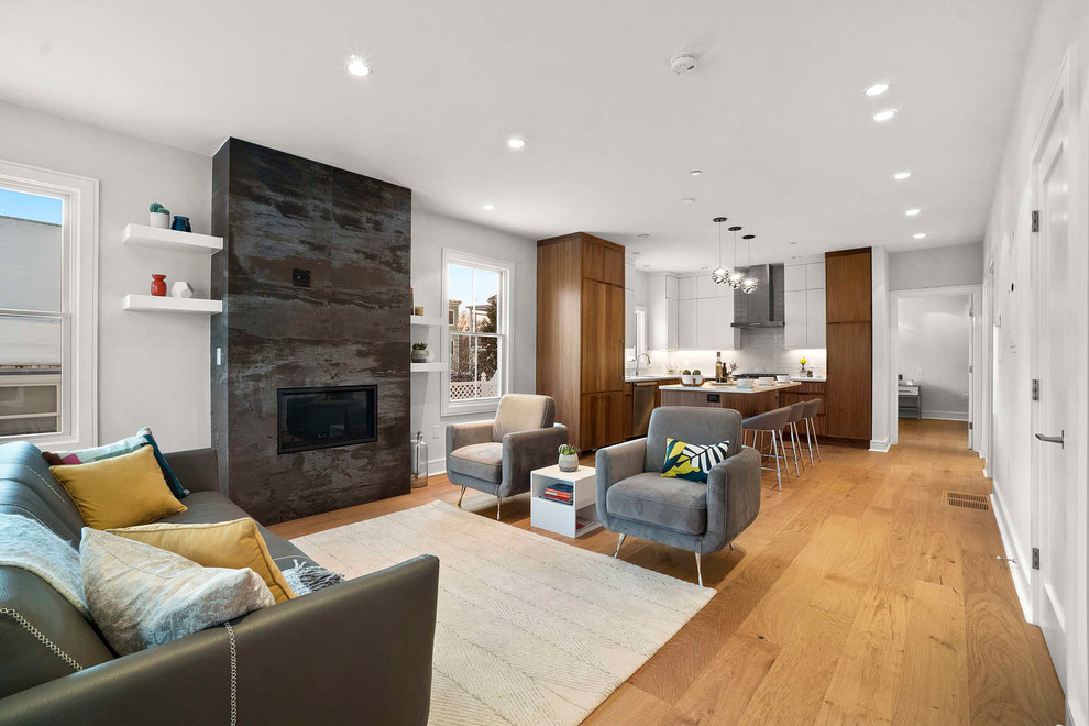 This is an example of a large modern loft-style living room in Boston with medium hardwood floors, a stone fireplace surround, a wall-mounted tv and brown floor.
