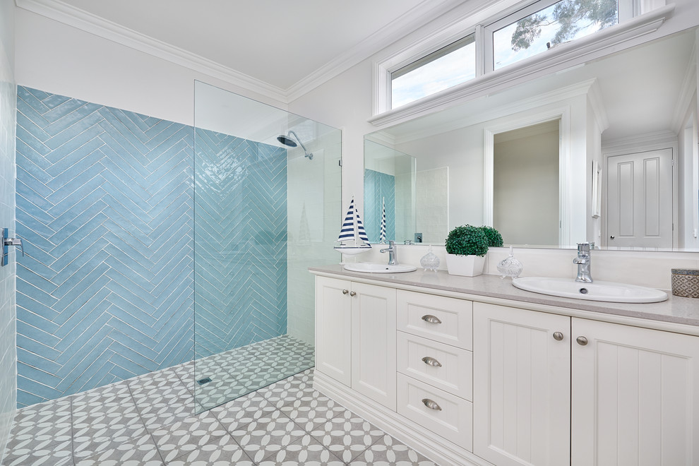 Photo of a beach style 3/4 bathroom in Melbourne with shaker cabinets, beige cabinets, an alcove shower, blue tile, beige walls, a drop-in sink, grey floor, an open shower and grey benchtops.