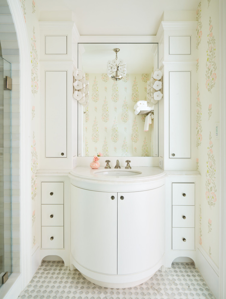 Exemple d'une petite douche en alcôve chic pour enfant avec des portes de placard blanches, une baignoire encastrée, WC à poser, un carrelage blanc, du carrelage en marbre, un mur multicolore, un sol en marbre, un lavabo encastré, un plan de toilette en marbre, un sol blanc, une cabine de douche à porte battante, un plan de toilette blanc, une niche, meuble simple vasque, meuble-lavabo encastré, du papier peint et un placard à porte plane.
