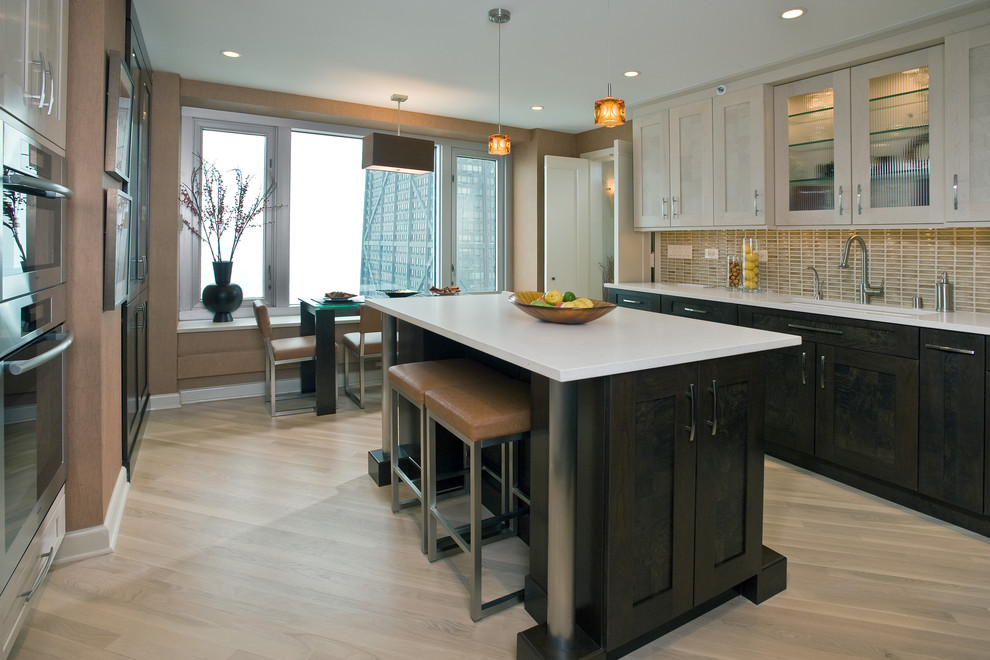 This is an example of a contemporary eat-in kitchen in Chicago with shaker cabinets, beige cabinets, beige splashback and stainless steel appliances.
