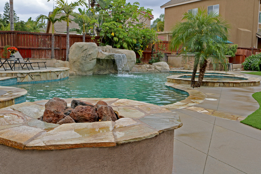 This is an example of a tropical backyard garden in Orange County with a fire feature.