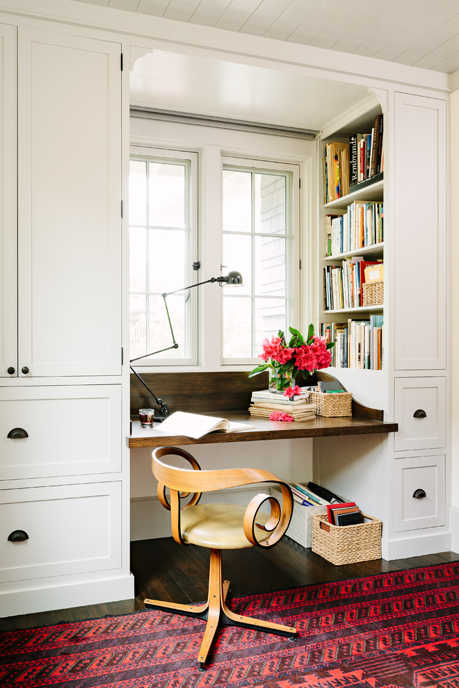 Photo of an arts and crafts home office in Portland with a built-in desk, white walls and dark hardwood floors.