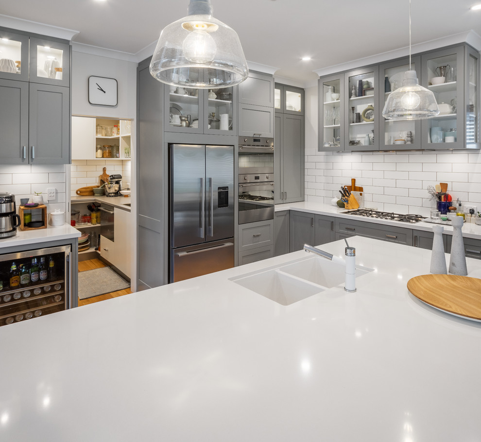 Design ideas for a transitional kitchen in Perth with an undermount sink, shaker cabinets, grey cabinets, quartz benchtops, white splashback, subway tile splashback, stainless steel appliances, with island and white benchtop.