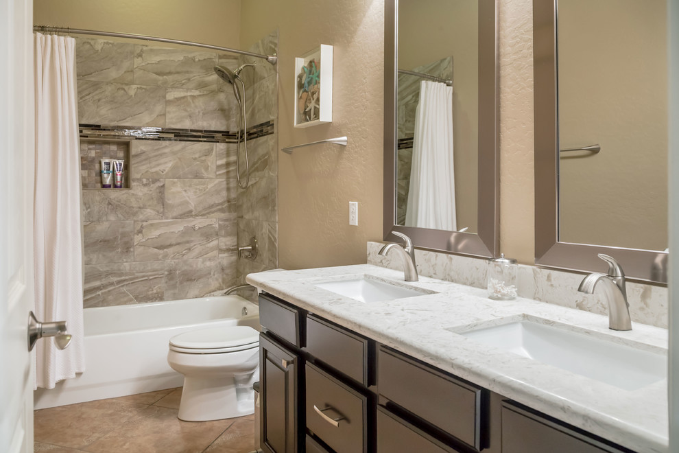 Example of a mid-sized transitional kids' brown tile ceramic tile alcove bathtub design in Phoenix with recessed-panel cabinets, brown cabinets, a two-piece toilet, beige walls, an undermount sink and quartz countertops
