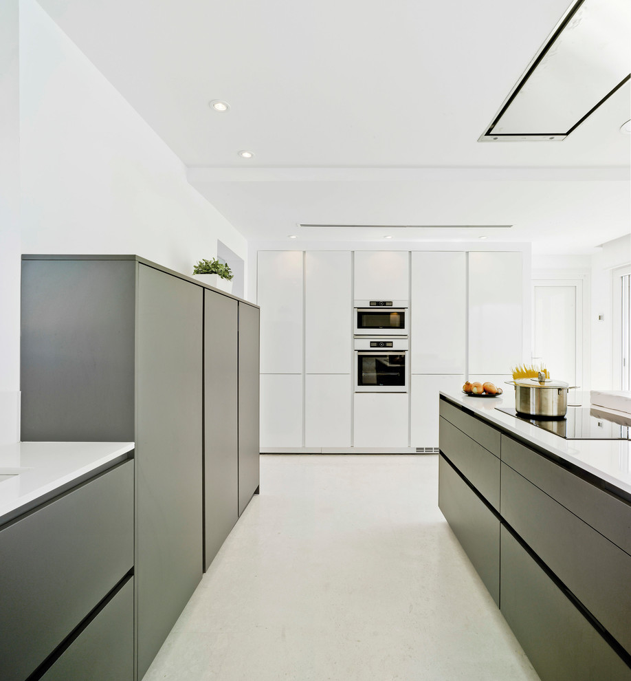 This is an example of a contemporary open plan kitchen in Other with an undermount sink, flat-panel cabinets, white cabinets, quartz benchtops, white appliances, porcelain floors, with island and white floor.