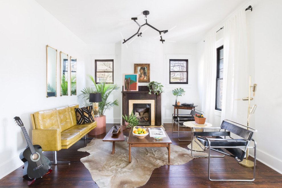Inspiration for an eclectic living room in Austin with white walls, dark hardwood floors, a standard fireplace and brown floor.