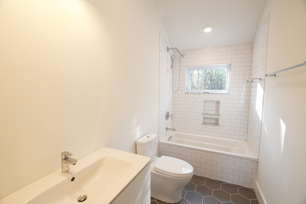 Mid-sized country kids bathroom in New York with flat-panel cabinets, white cabinets, an alcove shower, a one-piece toilet, white tile, ceramic tile, white walls, ceramic floors, an integrated sink, solid surface benchtops, grey floor, white benchtops, a single vanity, a freestanding vanity and vaulted.