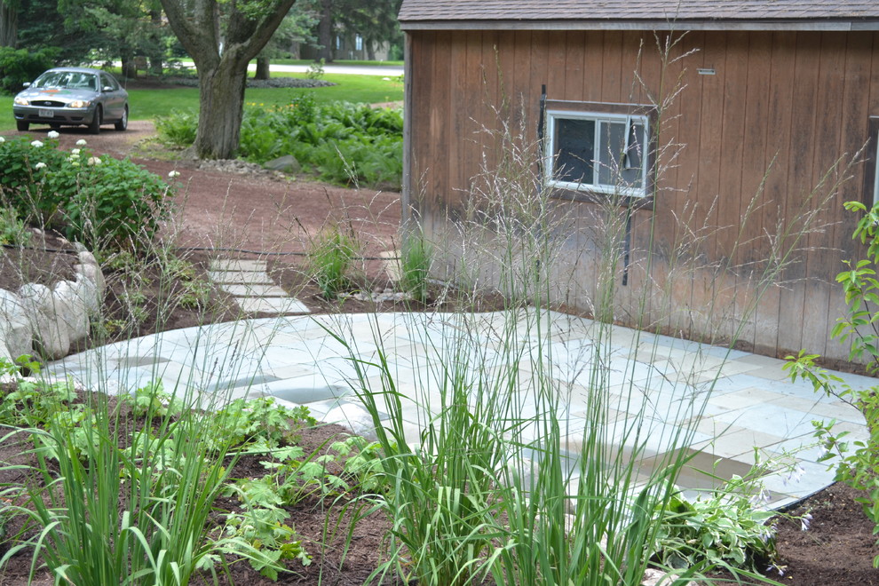 Photo of a mid-sized rustic backyard stone landscaping in Milwaukee.