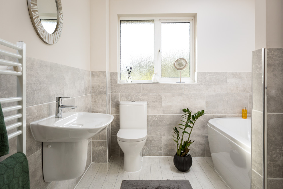 This is an example of a small contemporary kids bathroom in Other with a freestanding tub, a curbless shower, a one-piece toilet, gray tile, stone tile, white walls, linoleum floors and a wall-mount sink.