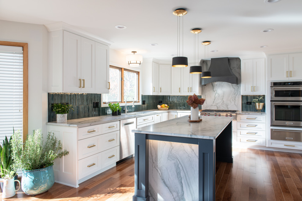 This is an example of a large transitional u-shaped eat-in kitchen in Chicago with a drop-in sink, shaker cabinets, white cabinets, quartzite benchtops, green splashback, porcelain splashback, stainless steel appliances, medium hardwood floors, with island, brown floor and grey benchtop.