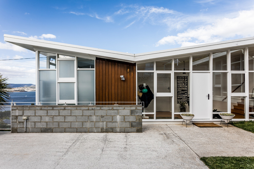 This is an example of a contemporary one-storey white house exterior in Hobart with mixed siding and a shed roof.