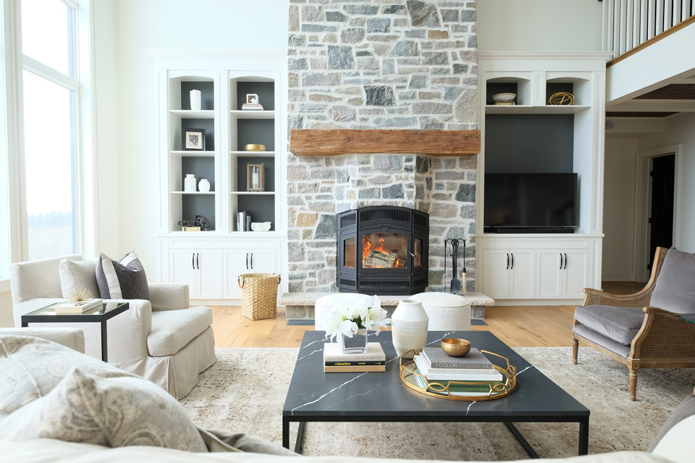 Photo of a country open concept family room in Toronto with white walls, light hardwood floors, a stone fireplace surround and a freestanding tv.