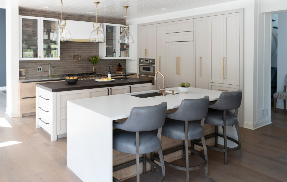 Mid-sized transitional l-shaped light wood floor, beige floor and wood ceiling open concept kitchen photo in Chicago with an undermount sink, glass-front cabinets, white cabinets, stainless steel countertops, brown backsplash, ceramic backsplash, colored appliances and two islands