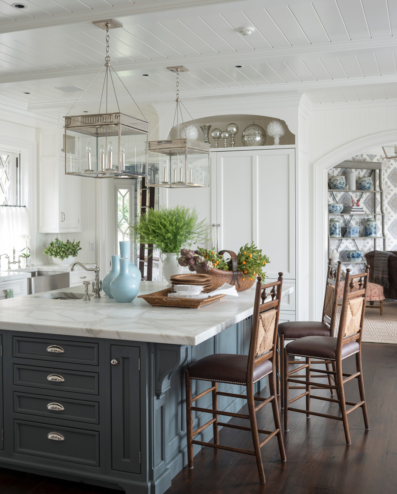 This is an example of a large traditional u-shaped kitchen in Other with a farmhouse sink, recessed-panel cabinets, white cabinets, marble benchtops, white splashback, panelled appliances, dark hardwood floors, with island and brown floor.