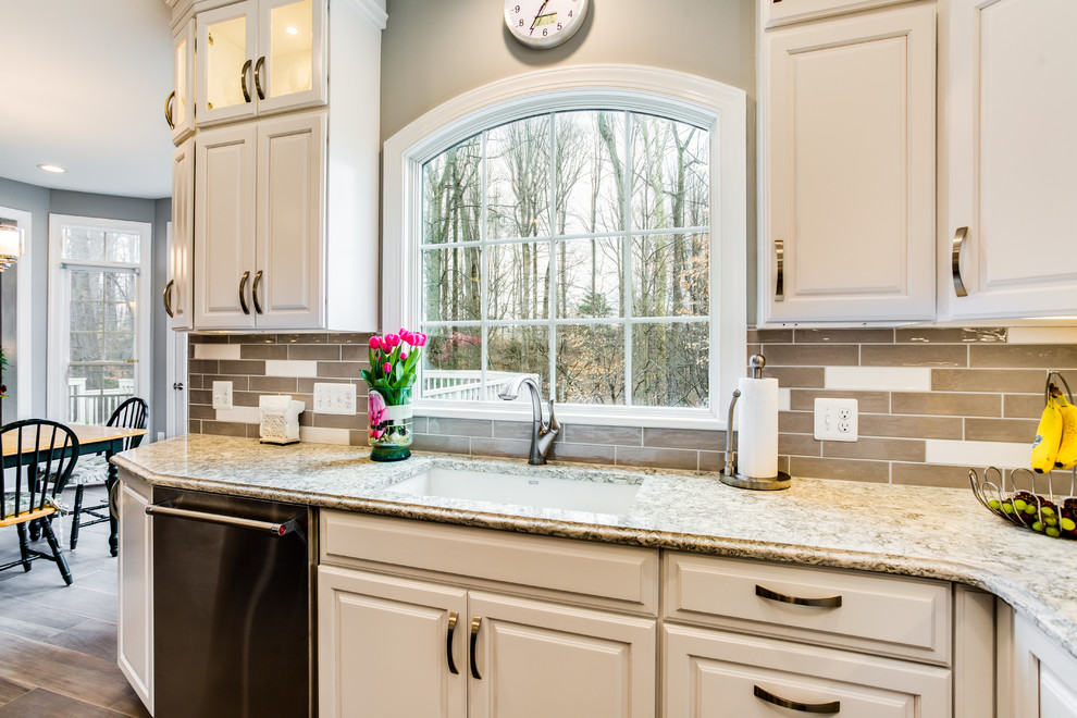 Example of a large transitional u-shaped porcelain tile and brown floor eat-in kitchen design in DC Metro with a single-bowl sink, raised-panel cabinets, white cabinets, quartz countertops, gray backsplash, ceramic backsplash, stainless steel appliances and an island