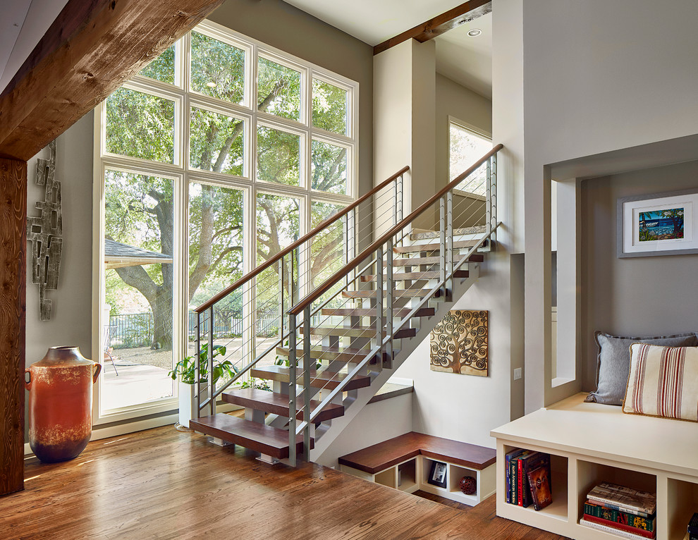 This is an example of a mid-sized transitional wood straight staircase in Dallas with open risers and cable railing.