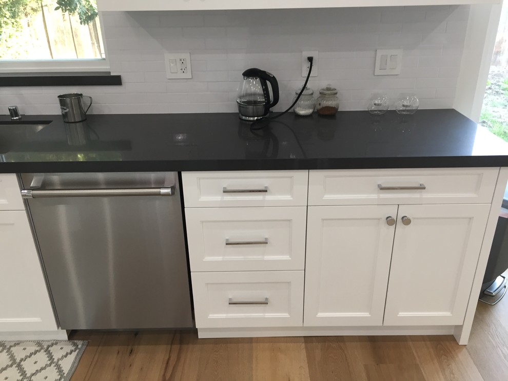 Inspiration for a mid-sized traditional l-shaped eat-in kitchen in San Francisco with a double-bowl sink, shaker cabinets, white cabinets, marble benchtops, white splashback, subway tile splashback, stainless steel appliances, light hardwood floors, with island and beige floor.