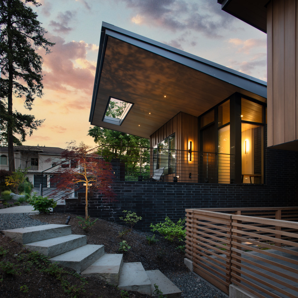 Inspiration för stora moderna verandor framför huset, med takförlängning och räcke i trä