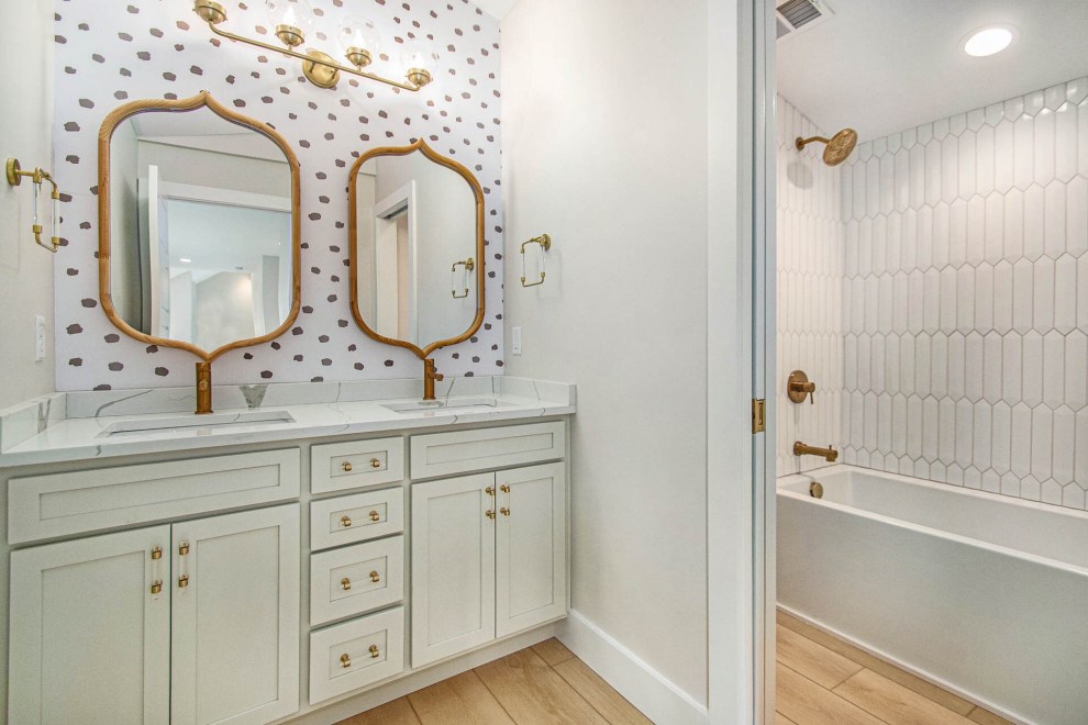 Photo of a medium sized modern shower room bathroom in Indianapolis with beaded cabinets, grey cabinets, a claw-foot bath, a shower/bath combination, white tiles, ceramic tiles, grey walls, vinyl flooring, a console sink, marble worktops, yellow floors, a shower curtain, white worktops, an enclosed toilet, double sinks, a built in vanity unit, a vaulted ceiling and wallpapered walls.
