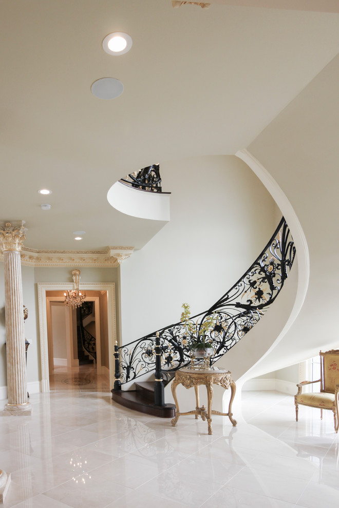 Expansive traditional wood curved staircase in DC Metro with wood risers and metal railing.