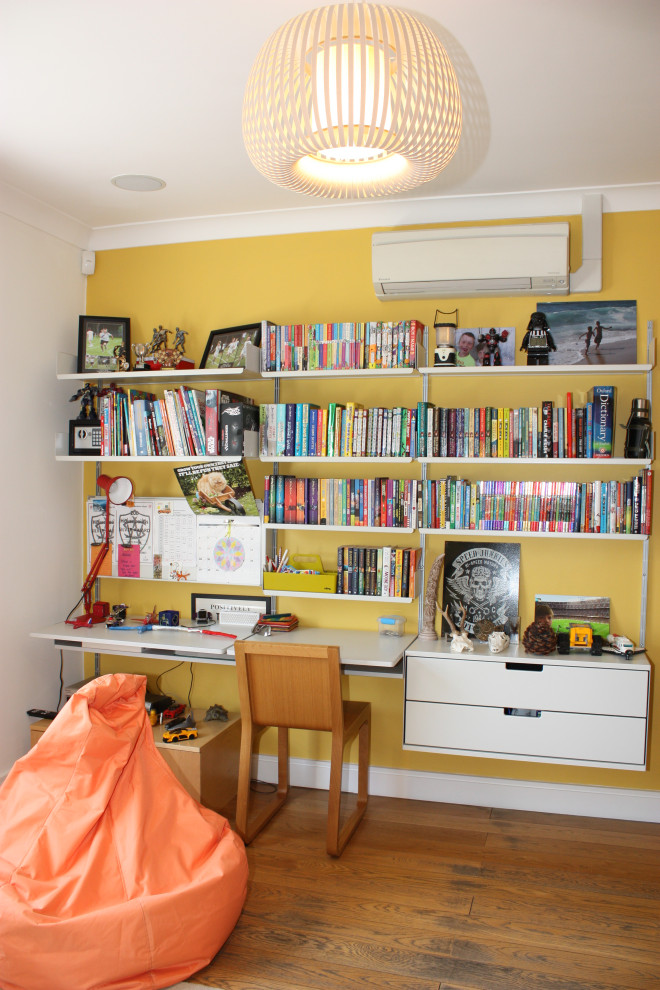 Inspiration för ett stort funkis barnrum kombinerat med sovrum, med gula väggar och mellanmörkt trägolv